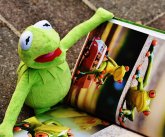 Eine Kuschelfigur von Kermit dem Frosch "liest" ein Bilderbuch